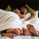 Lovely couple kissing in bed, focus on feet